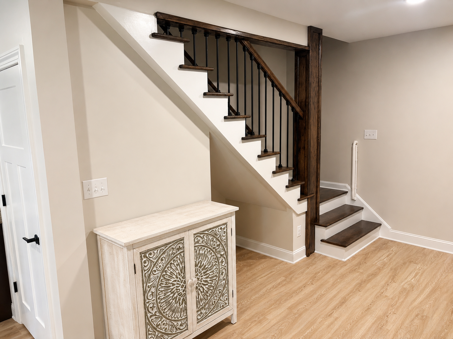 Basement Build Out — staircase close-up with dark wood railings, white risers, and decorative cabinet by Luxe Built Louisville KY