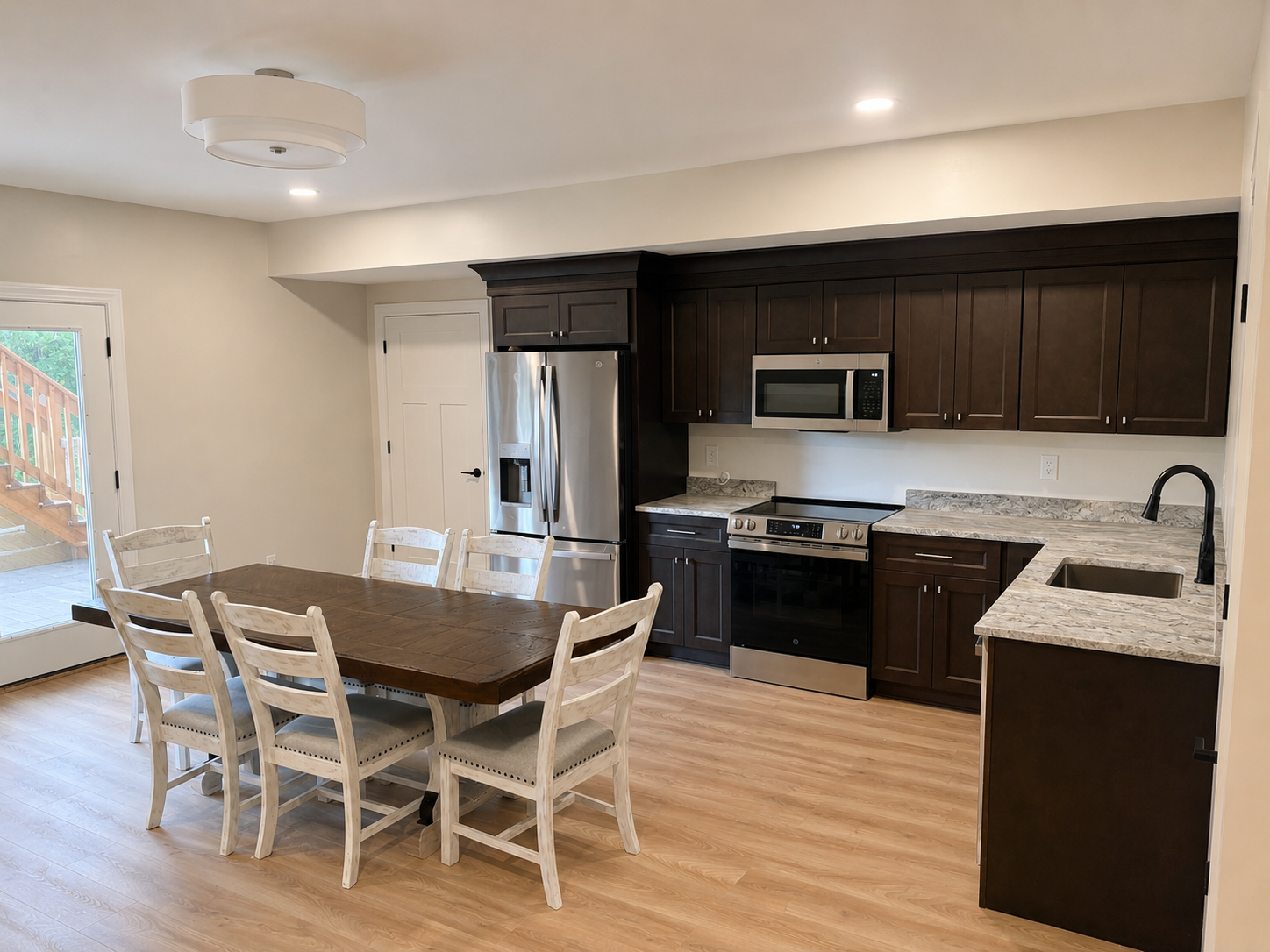 Basement Build Out — full kitchen and dining area with dark espresso cabinetry, granite countertops, stainless appliances, and farmhouse table by Luxe Built Louisville KY