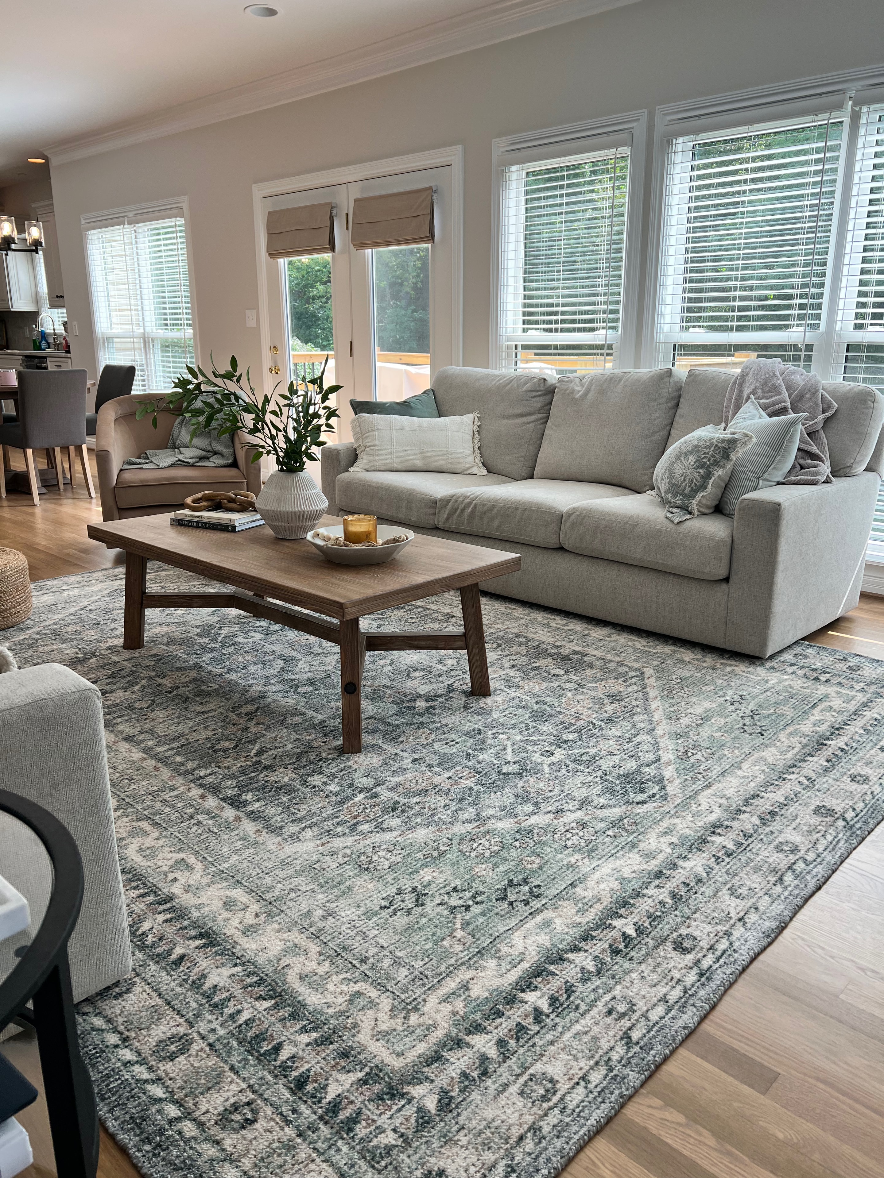 Living Room & Kitchen remodel — living room seating area with gray sofa, patterned rug, and hardwood floors by Luxe Built Louisville KY