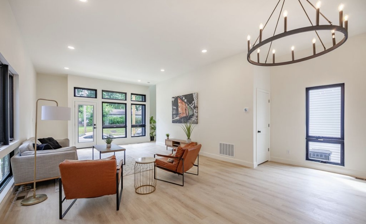 The Narrow House — living room with sofa, leather accent chairs, and open view to kitchen and rear windows by Luxe Built Louisville KY