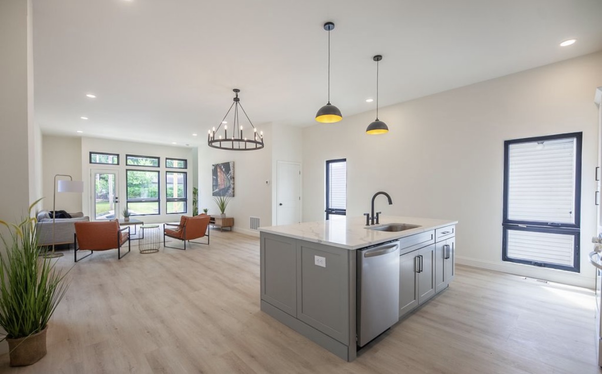 The Narrow House — kitchen and living room open plan with island, pendant lights, and rear garden view by Luxe Built Louisville KY
