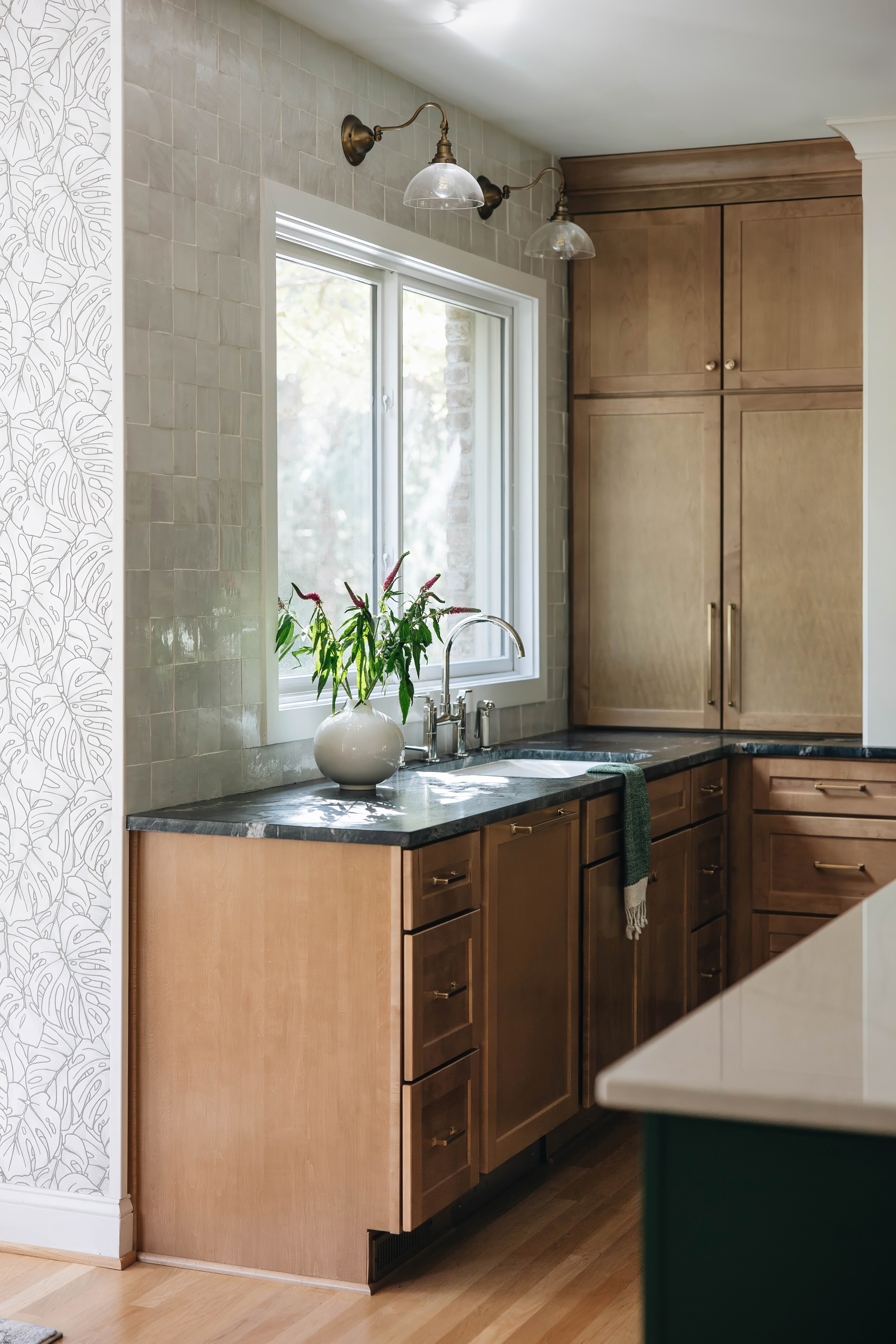 Seneca Gardens kitchen — open plan view from living room showing green island, integrated refrigerator, and brass hardware by Luxe Built